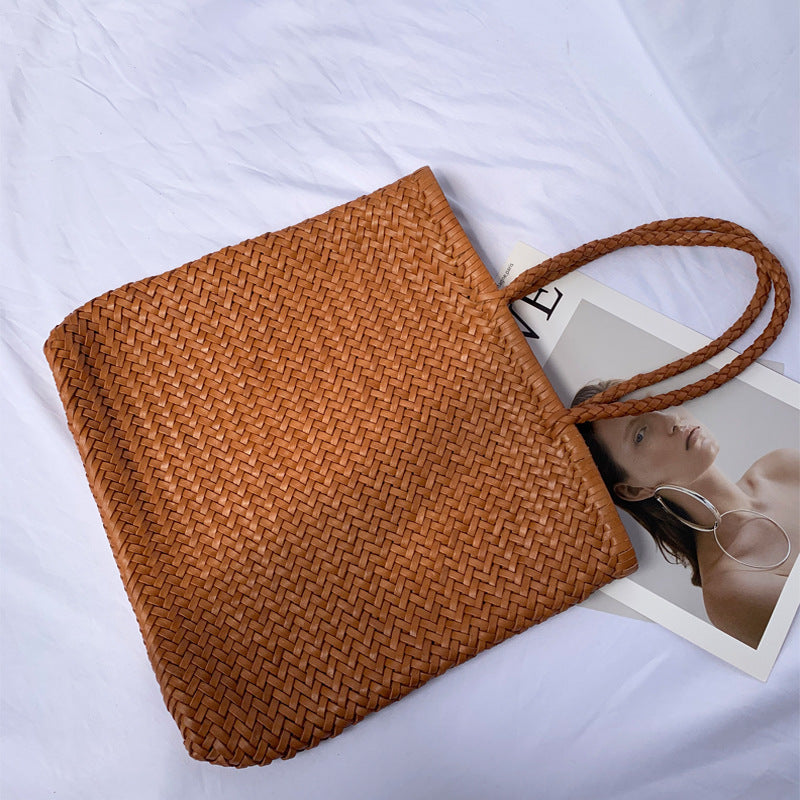 Brown woven bag on a white surface with a magazine underneath