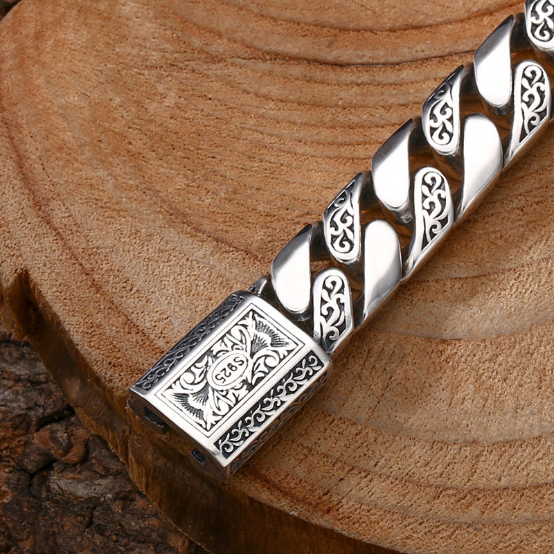 Silver bracelet with intricate designs on a wooden surface