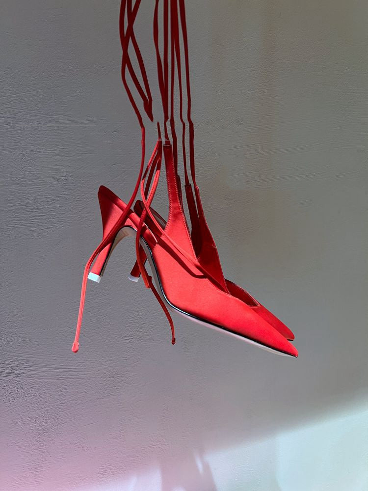 Red high-heeled shoes hanging against a light gray background