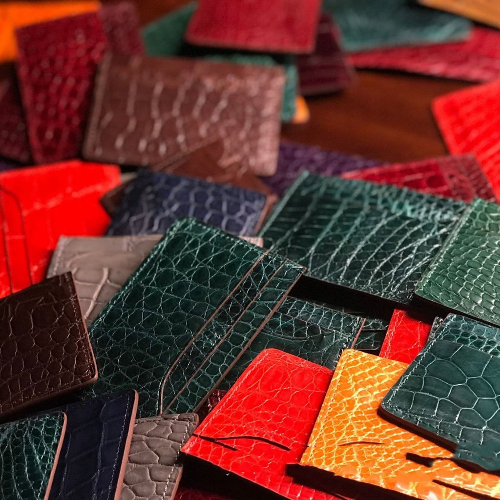 Collection of various colored leather card holders on a wooden surface