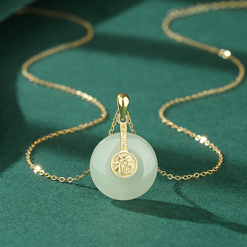 Gold necklace with a jade pendant on a green background