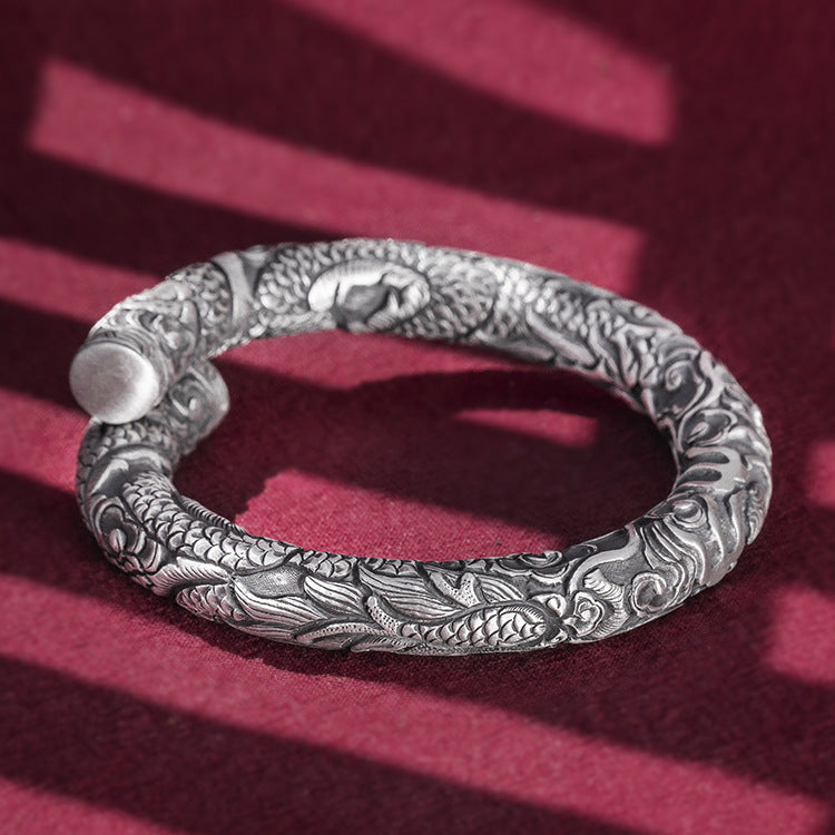 Silver bracelet with intricate designs on a red background