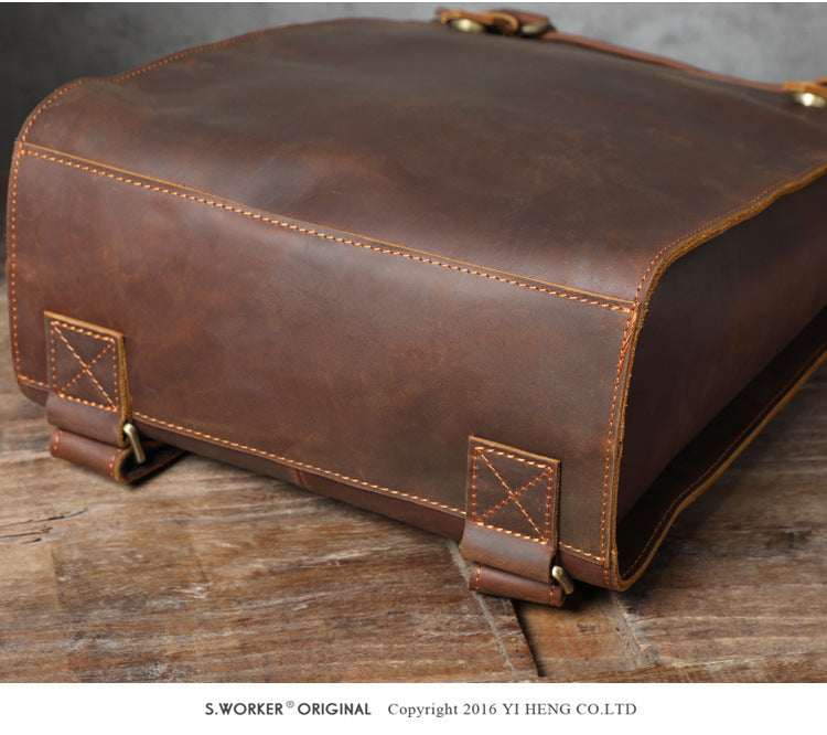 Brown leather bag with gold stitching on a wooden surface