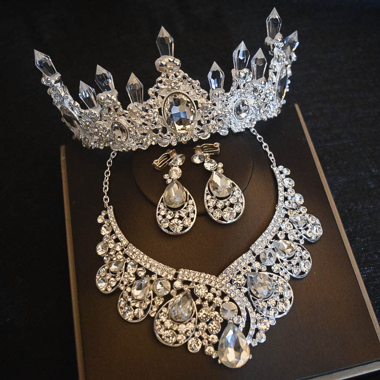 Silver jewelry set with tiara, necklace, and earrings on a dark background