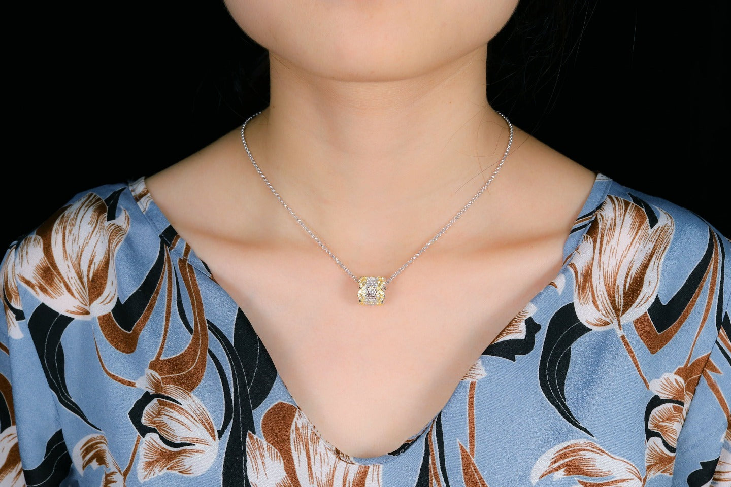 Necklace with a pendant worn by a person against a dark background