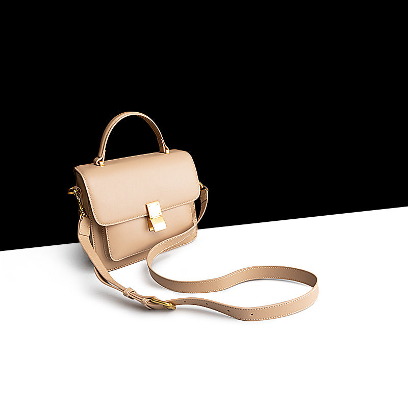 Beige handbag with a strap on a white surface with a black background