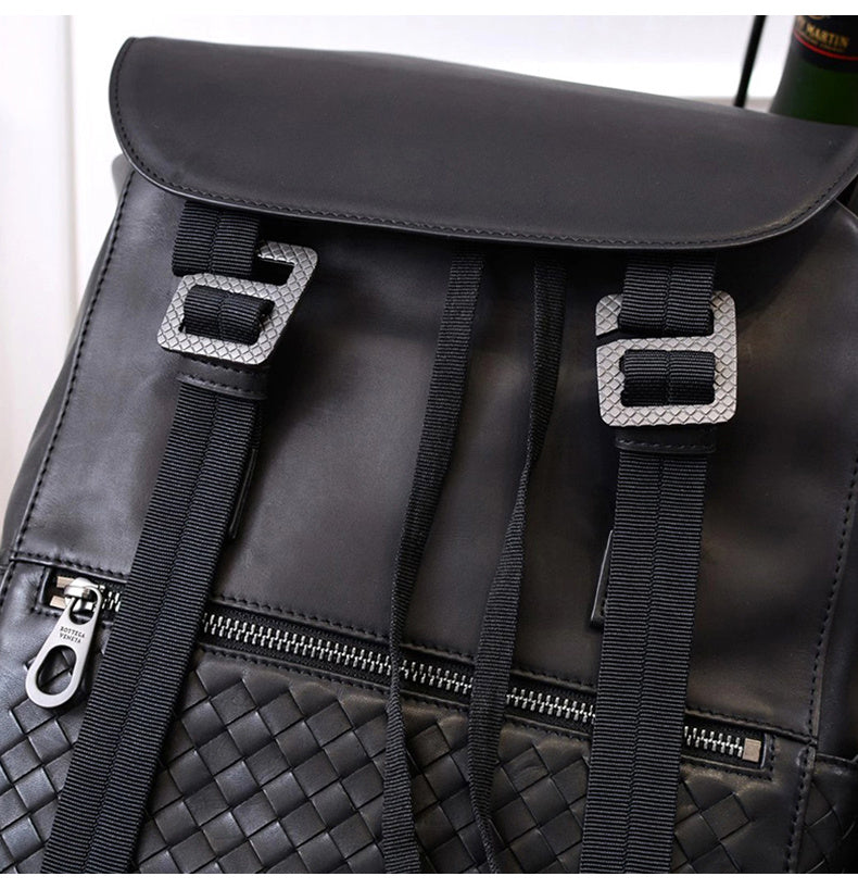 Black leather backpack with woven pattern and silver buckles on a white background