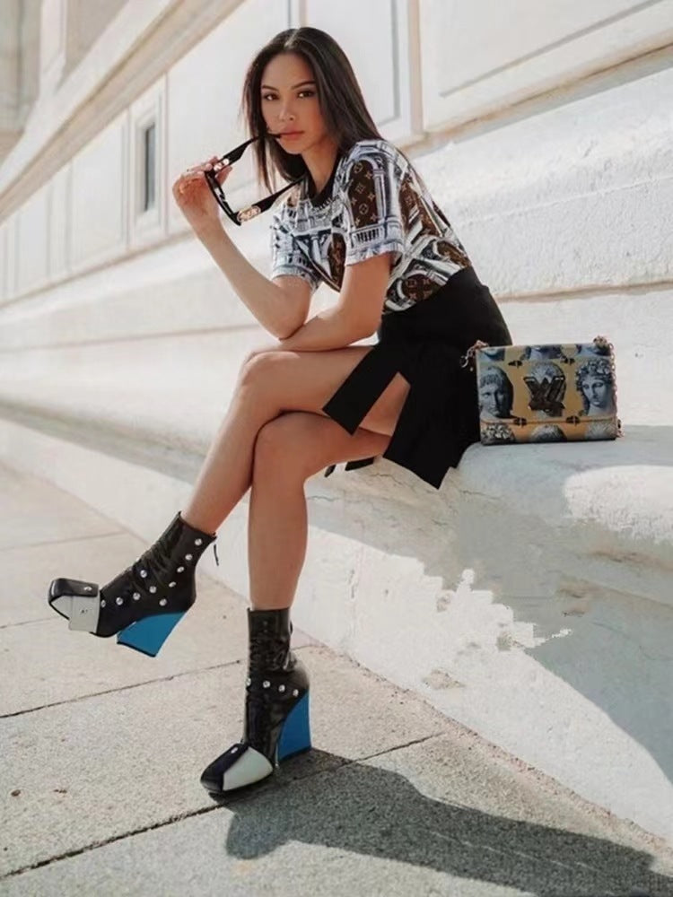 Woman sitting on a bench wearing a patterned shirt, black skirt, and black and blue shoes.
