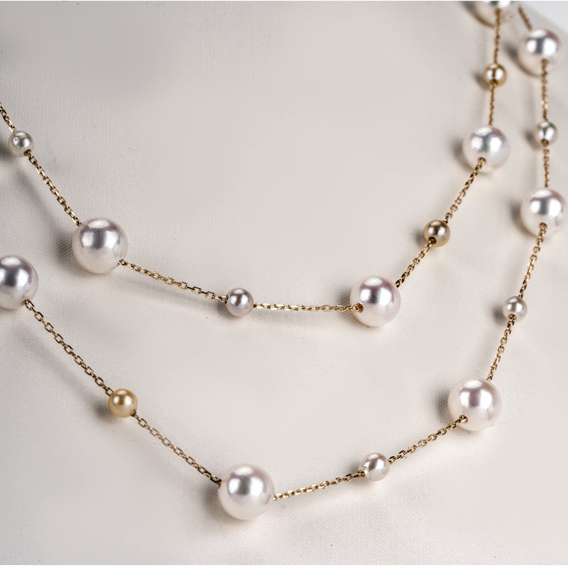 Pearl necklace with gold chain on a light background