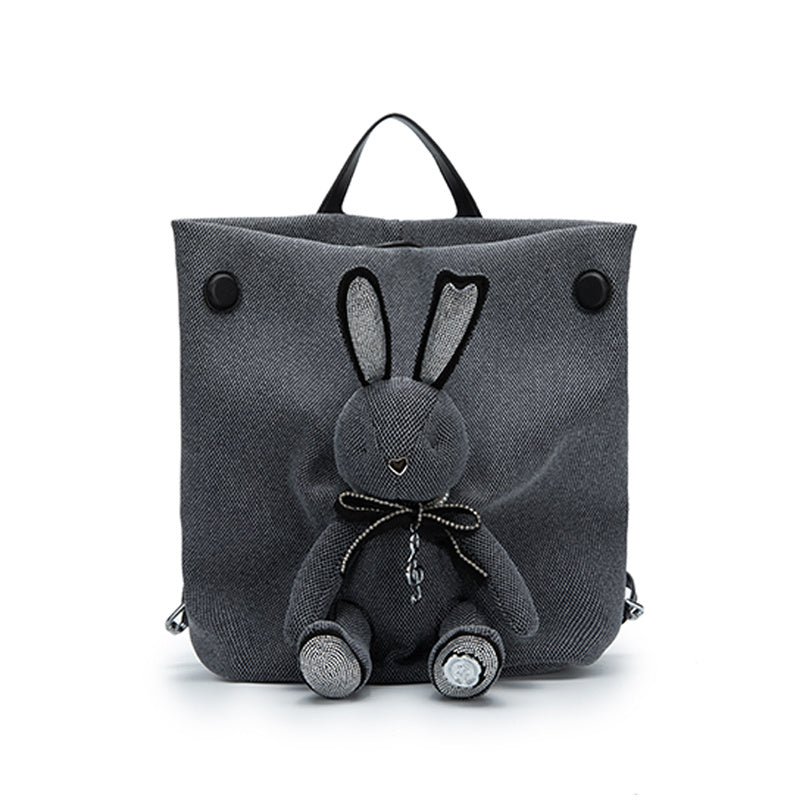 Gray backpack with a plush rabbit toy on a white background