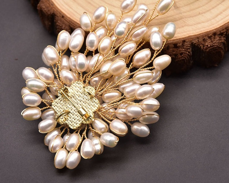 Pearl brooch with gold center on a wooden surface