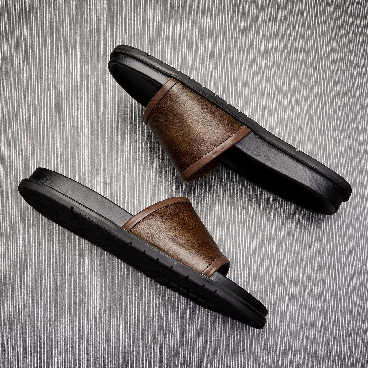Brown sandals with black soles on a textured gray background