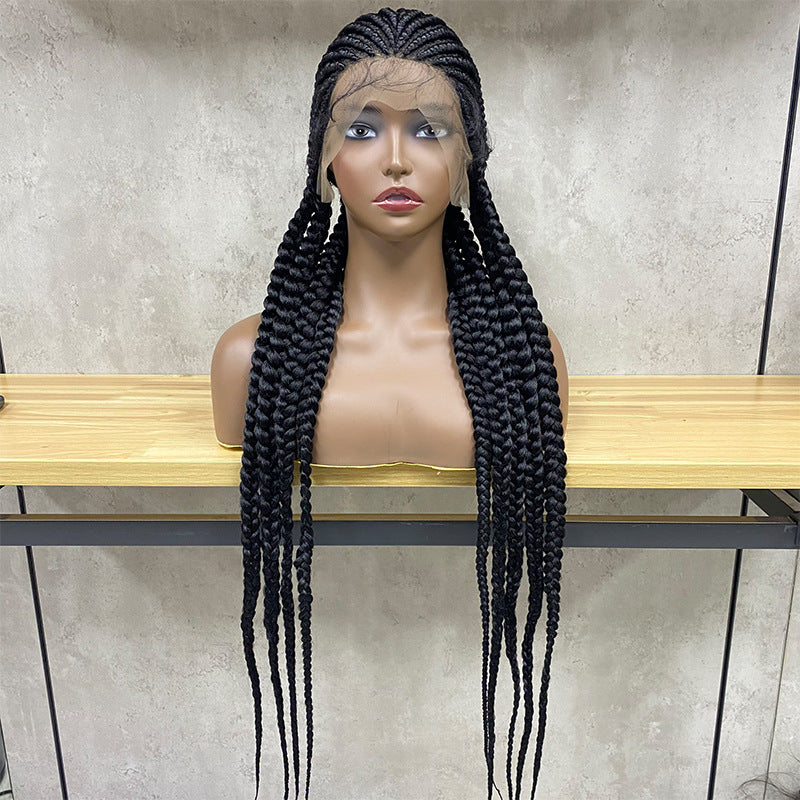 Mannequin head with long braided wig on a wooden stand against a neutral wall.