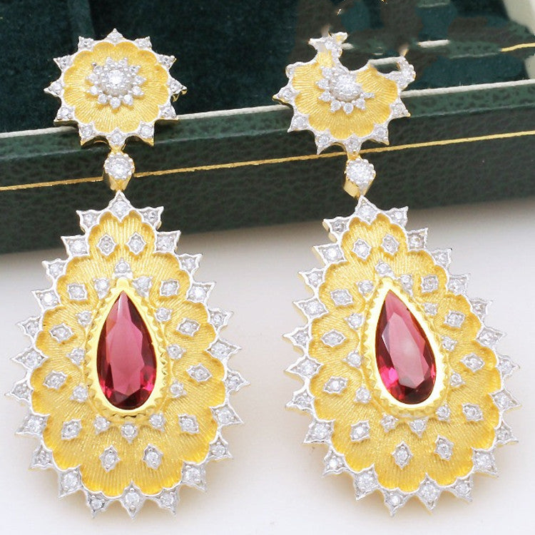 Gold earrings with red gemstones on a white background