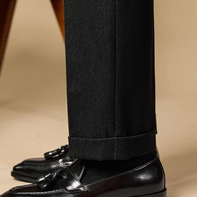 Black dress shoes and pants on a beige background