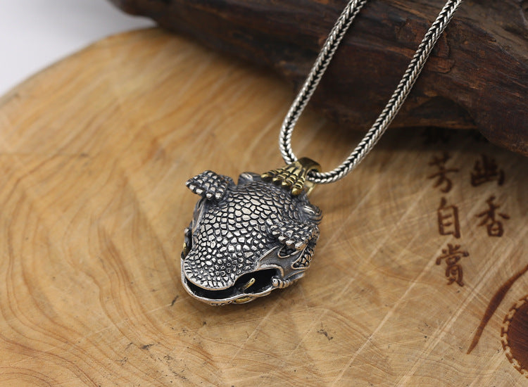 Silver fish-shaped pendant on a wooden surface with engraved text