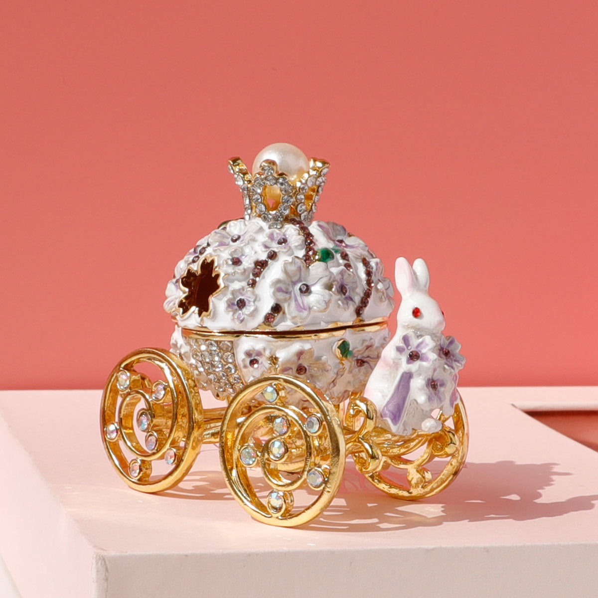 Decorative horse-drawn carriage with a rabbit figure on a pink surface and background
