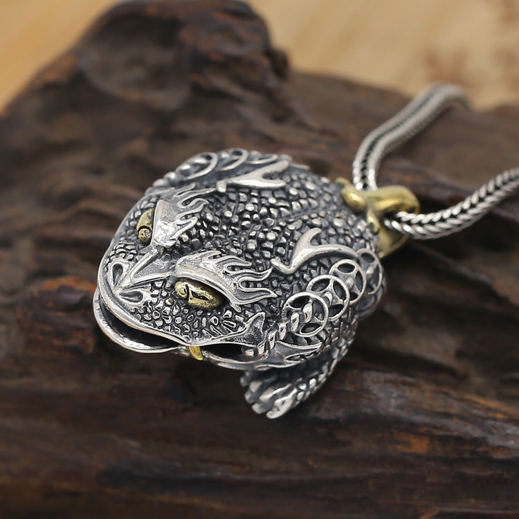 Silver dragon pendant on a wooden surface