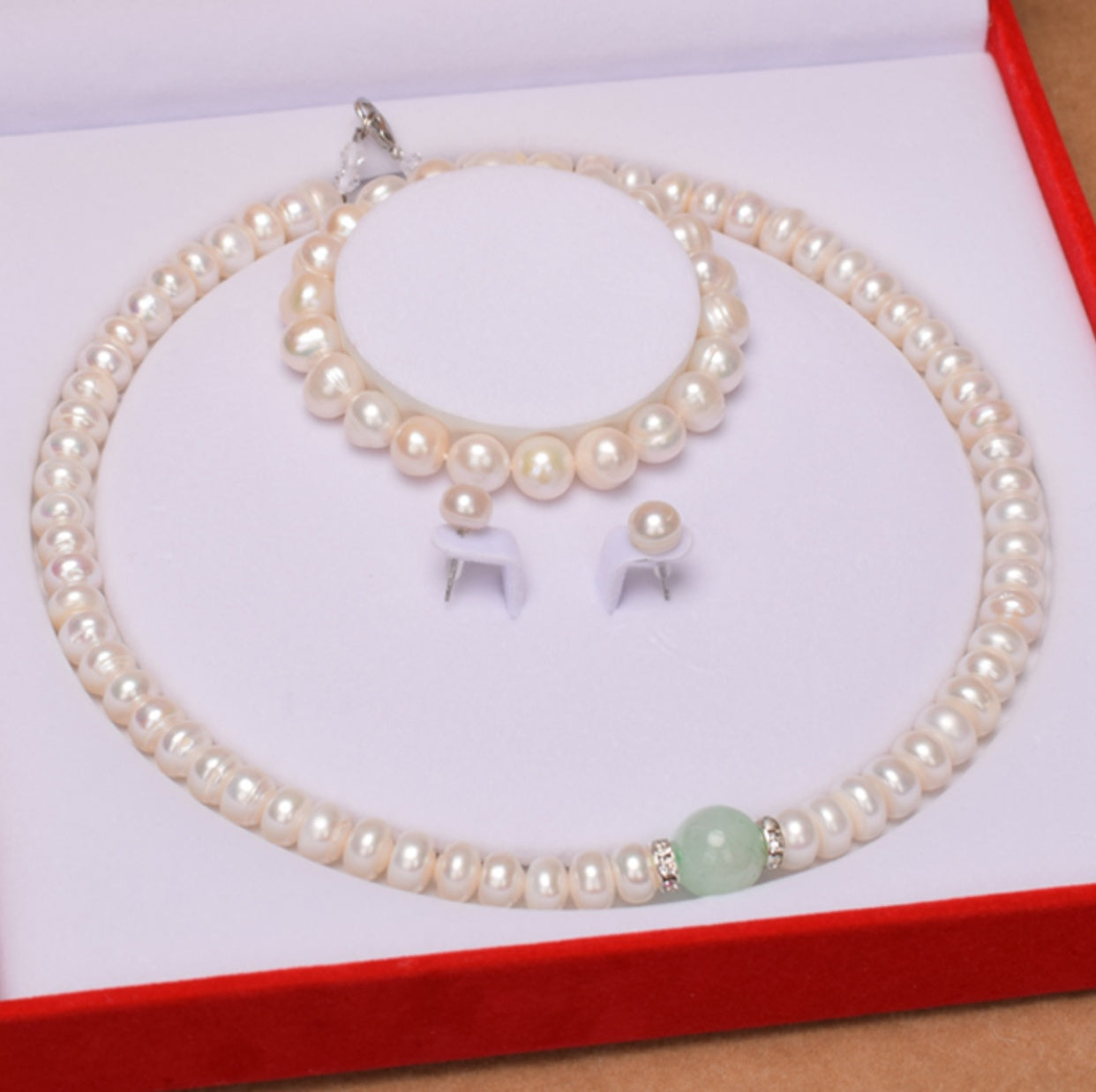 Pearl necklace and earrings set on a white card with a red border