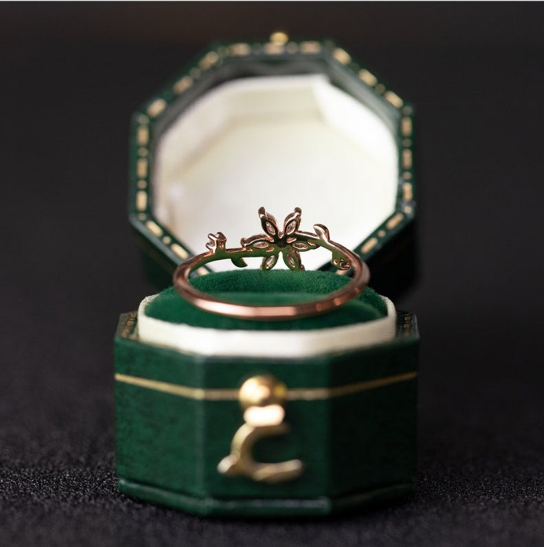 Gold ring with leaf design in a green jewelry box on a dark background