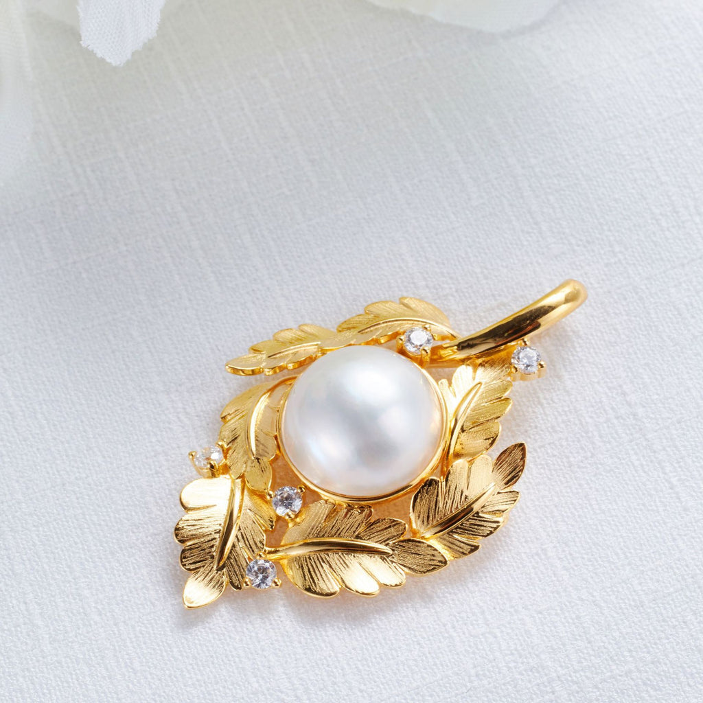 Gold pendant with a pearl and small diamonds on a white background