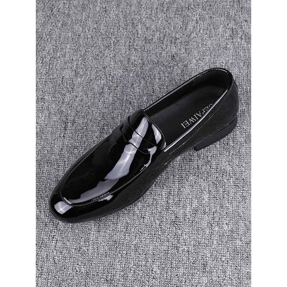 Black patent leather loafer on a gray textured background