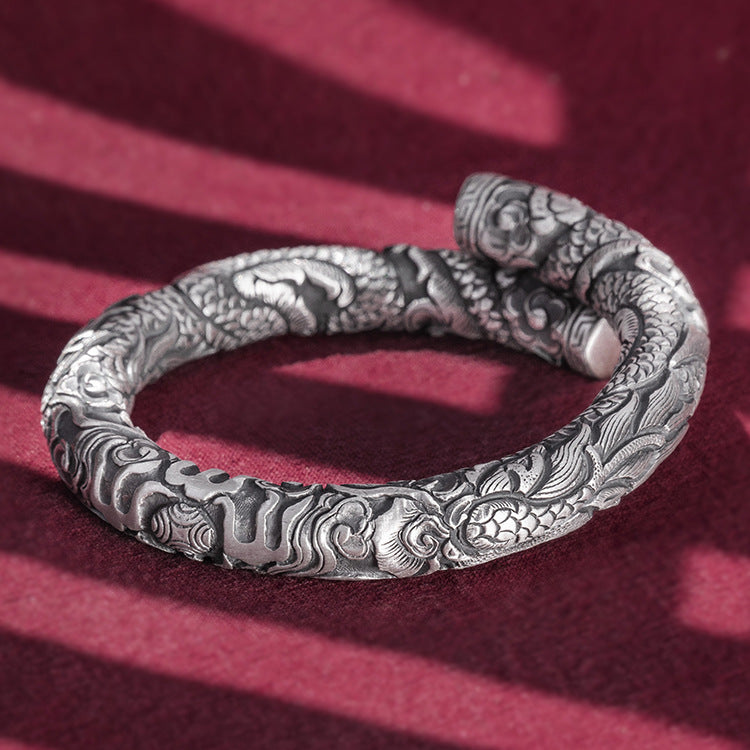 Silver bracelet with intricate designs on a red background