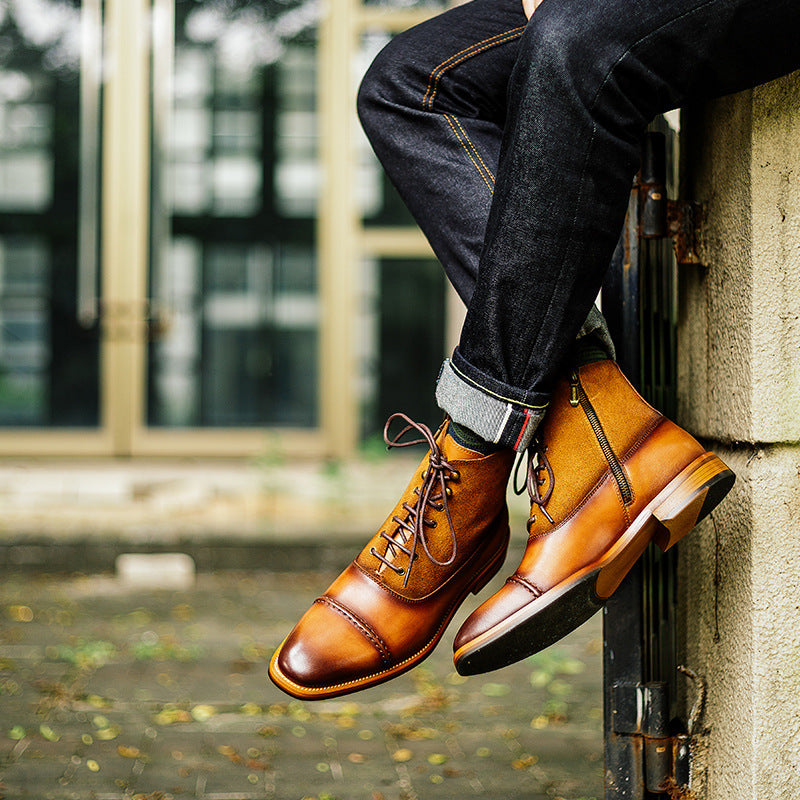 Person wearing brown leather shoes and dark jeans leaning against a wall.
