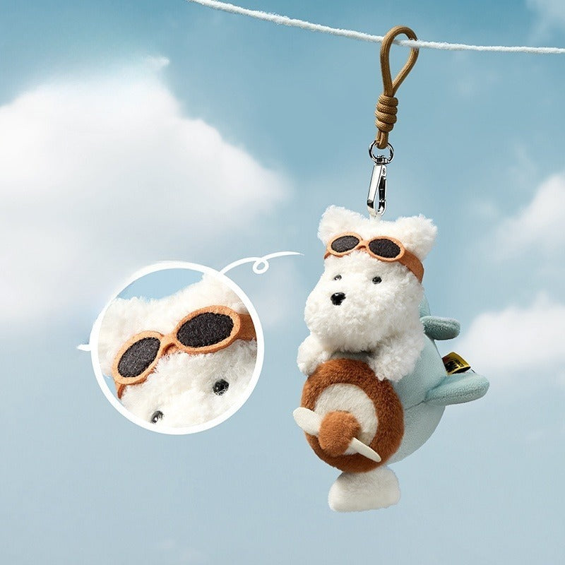 Plush keychain of a bear in an airplane with sunglasses against a blue sky background