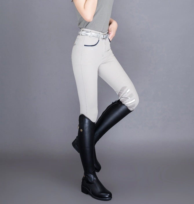 Person wearing white leggings and black riding boots on a gray background