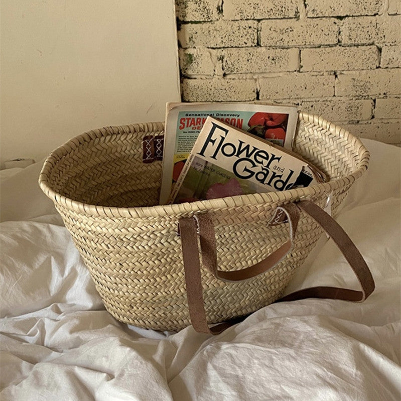 Woven basket with books on a bed against a brick wall