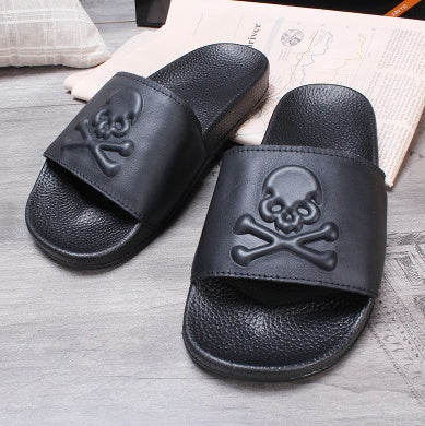 Black slides with skull design on a wooden floor