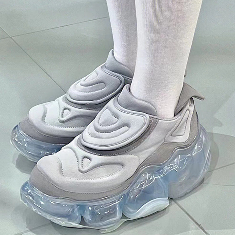 White and gray sneakers with transparent soles on a light gray floor.