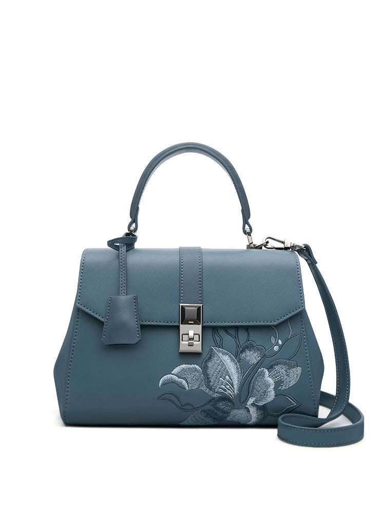 Blue handbag with floral embroidery on a white background