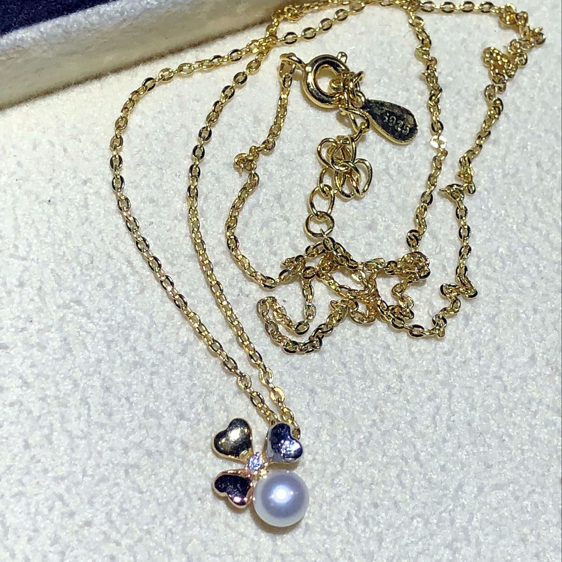 Gold necklace with a pearl pendant on a white background