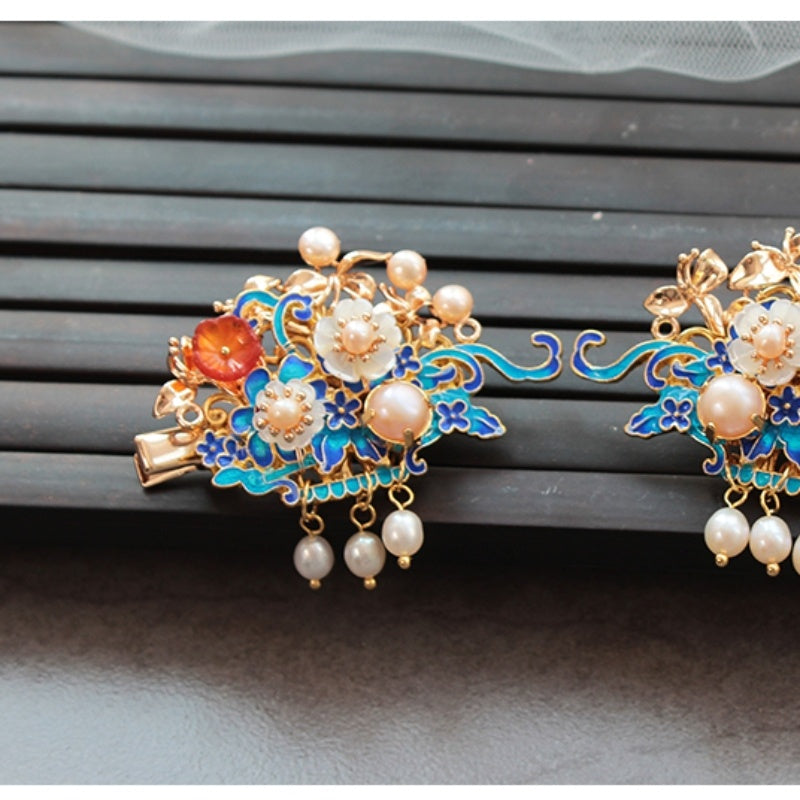 Decorative earrings with floral designs and pearls on a dark surface