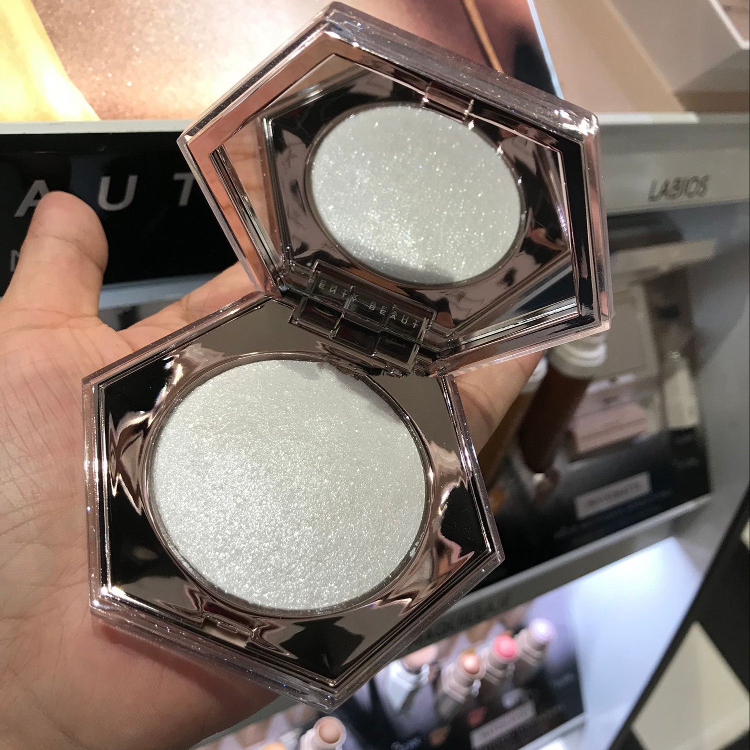 Compact powder in a hexagonal case held by a hand with a blurred background
