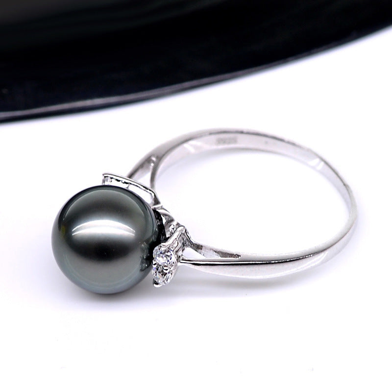 Silver ring with a large black pearl and small diamond on a white background