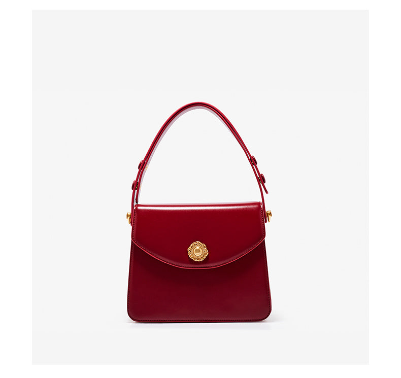 Red handbag with a gold emblem on a white background
