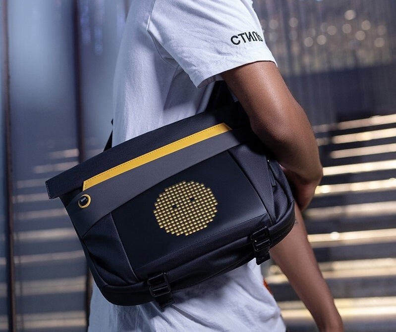 Person wearing a black bag with a gold circular design, standing on a staircase.