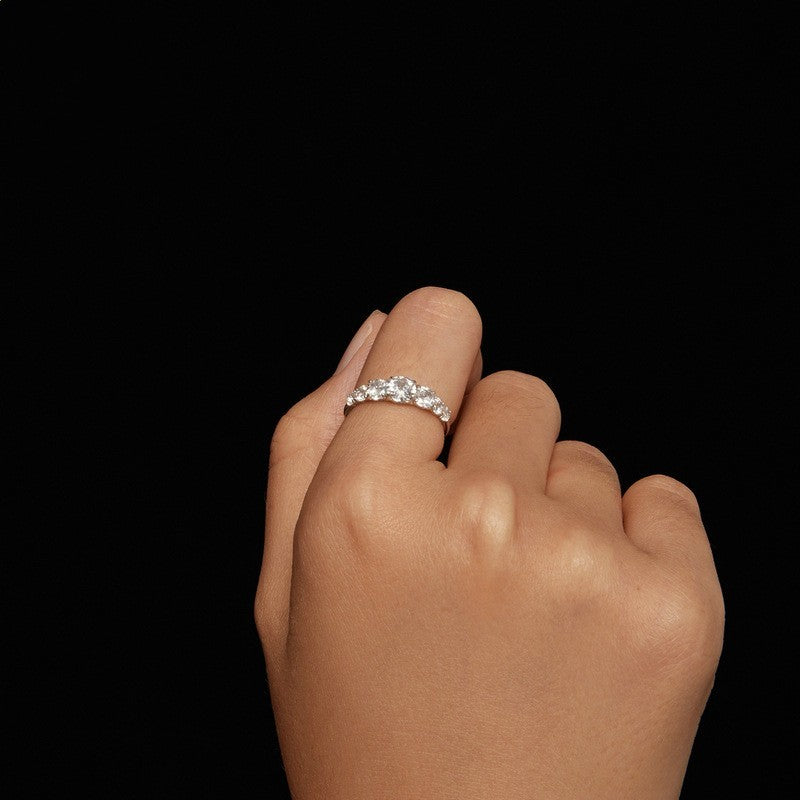 Hand wearing a silver ring with a clear gemstone on a black background