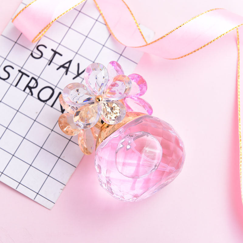 Pink perfume bottle with floral design on a pink and gold fabric background