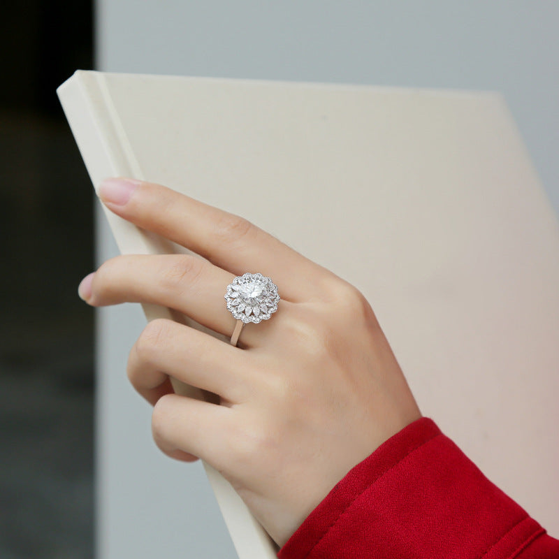 Hand wearing a diamond ring holding a book against a neutral background