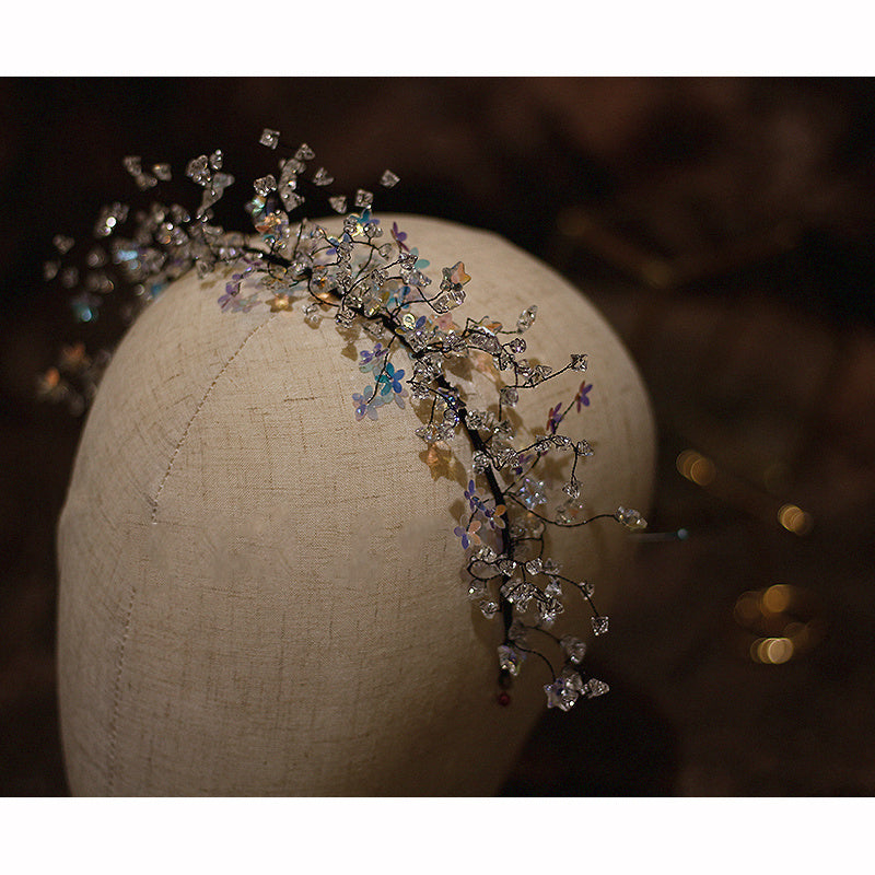 Decorative headband with flowers and beads on a mannequin head against a dark background