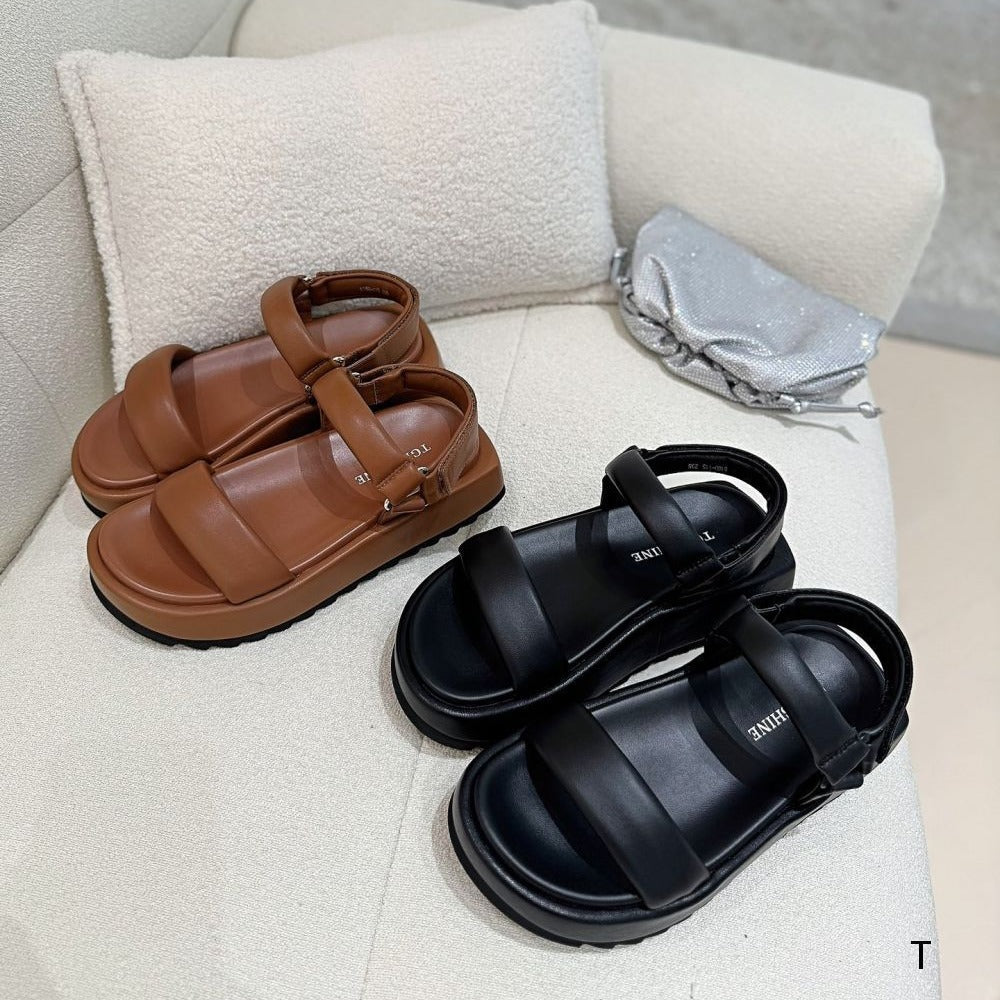 Brown and black sandals on a light-colored surface with a neutral background