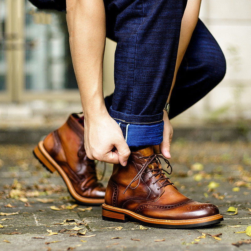 Person wearing brown leather shoes and blue pants, adjusting the pants with a blurred background.