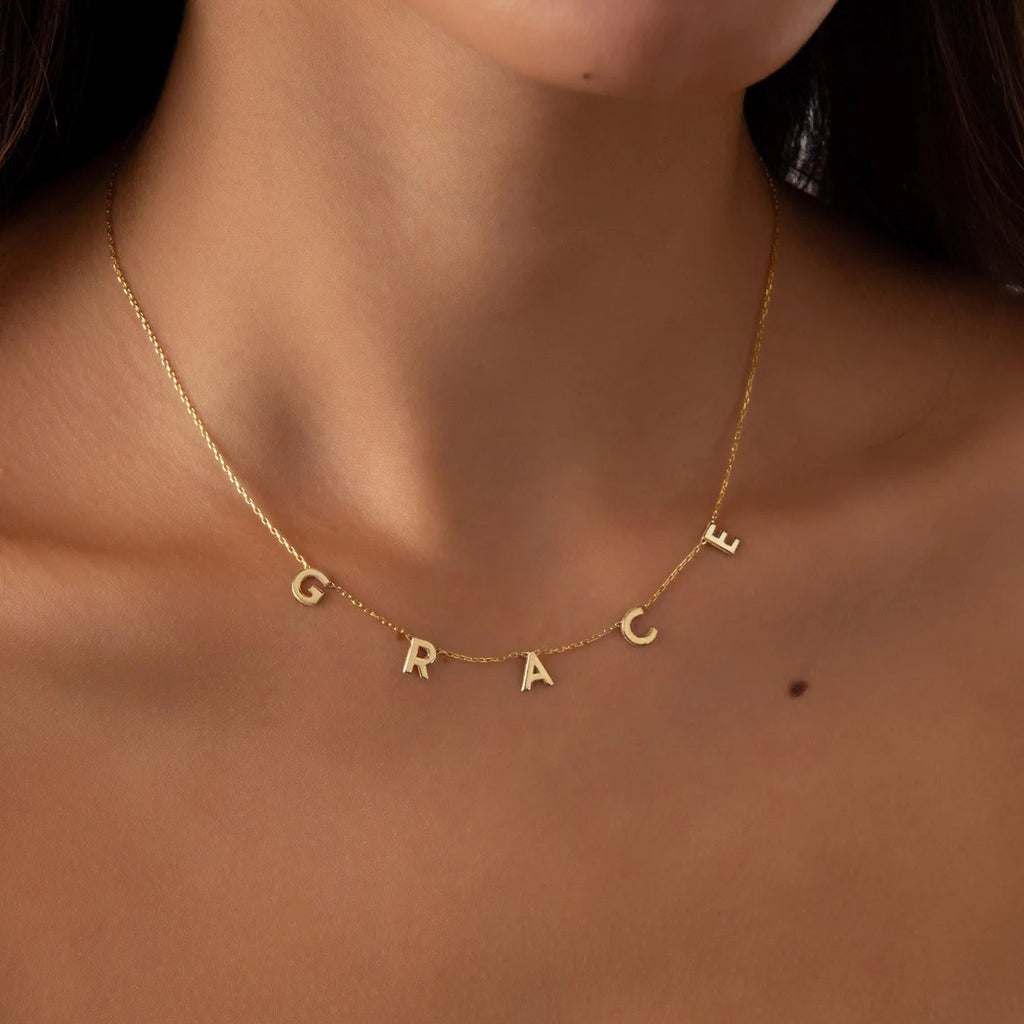 Gold necklace with 'GRACE' pendant on a person's neck