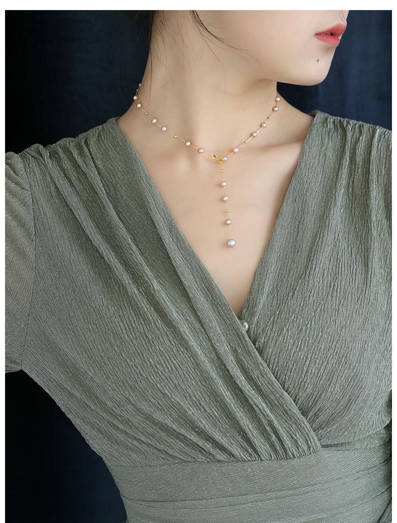 Woman wearing a green dress with a pearl necklace