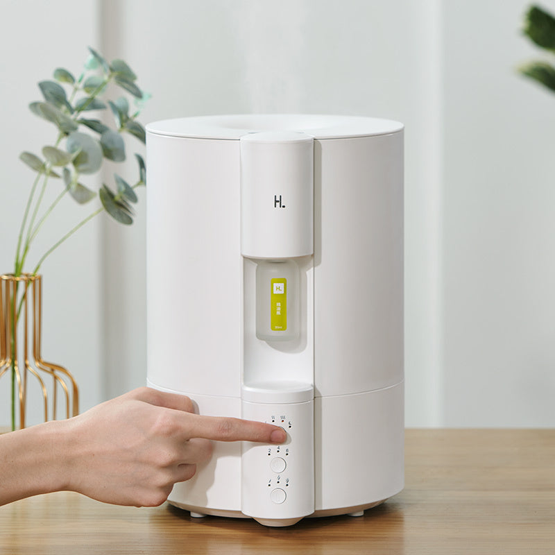 White water dispenser with a hand pointing at it on a wooden surface.