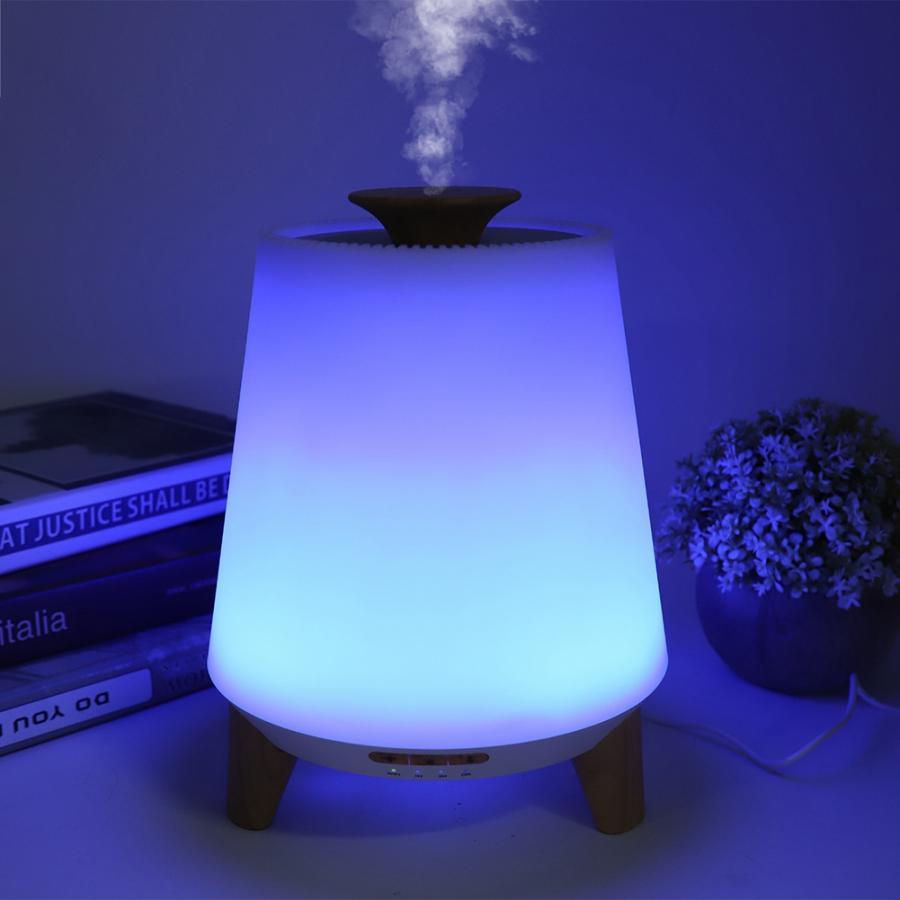 A humidifier emitting mist with a colorful light display on a table.